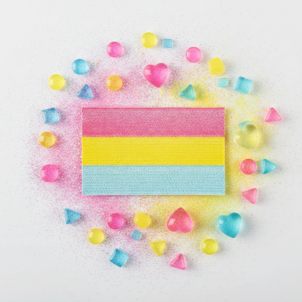 Pansexual Pride iron-on patch with a pink, yellow, and blue striped rectangle, gems, and hearts on glittery white fabric.