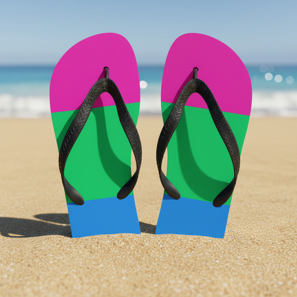Pansexual Pride flip-flops rocking pink, yellow, and blue blocks with black straps stand in sand