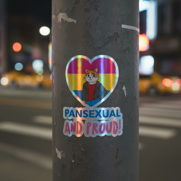 Holographic “Pansexual and Proud!” sticker with a cute cat in a heart of pan flag colors, on street pole, city lights behind.