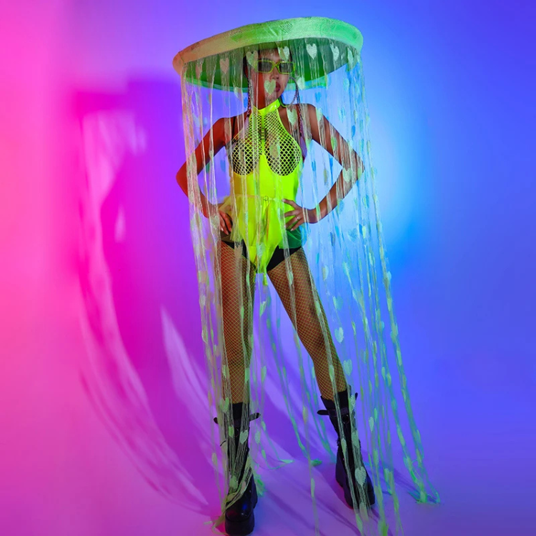 Model in neon yellow-green bodysuit, fishnet tights, platform boots, and jellyfish hat