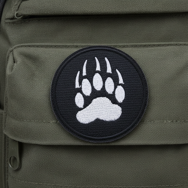 Paw Print Iron-On Embroidered Patch with bold black bear paw and claws, outlined in black, on olive green fabric.