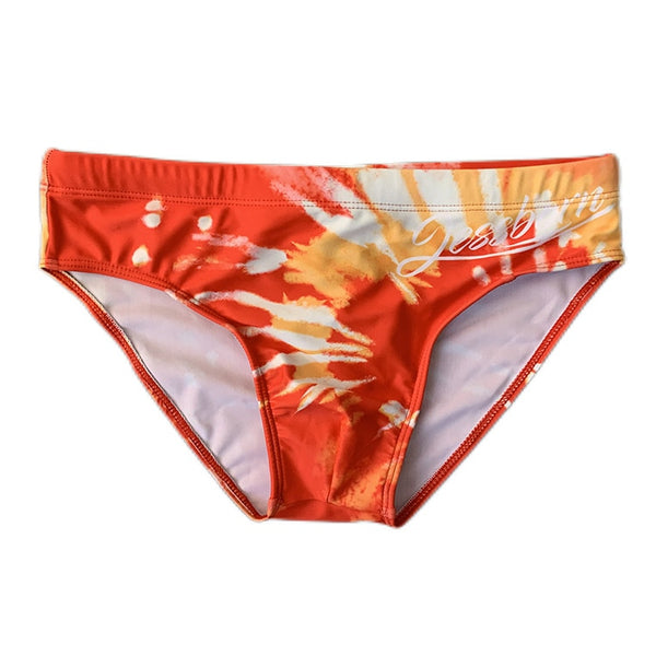 Front view of red-orange swim briefs with a white and gold brushstroke pattern and cursive text