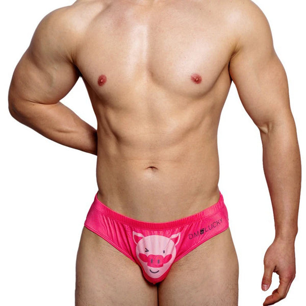 Front-facing shirtless model wearing bright pink brief underwear with a cartoon pig pouch
