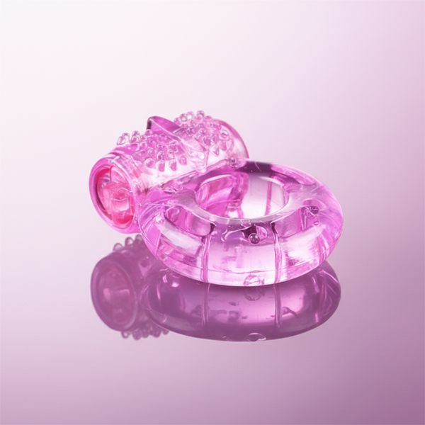 Translucent pink vibrating cock ring with a textured sleeve, shown at an angle on a reflective pink surface