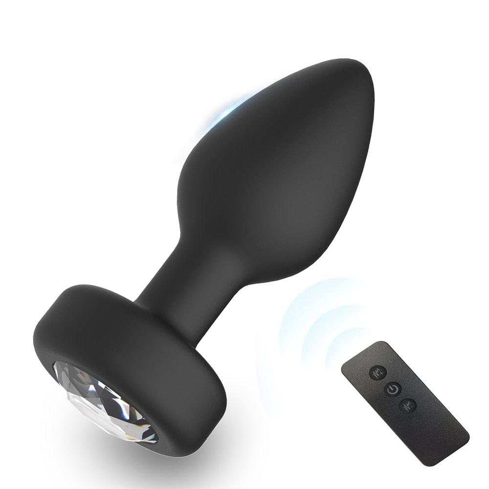 Black vibrating anal plug with faceted base beside a three-button remote