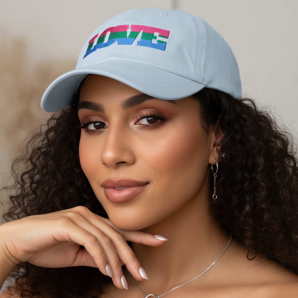 Polysexual Love Cap in pale blue with vibrant "LOVE" embroidery, worn by a curly-haired woman sporting queer femme vibes.
