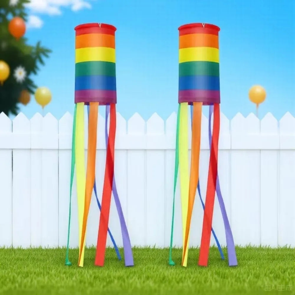 Two rainbow-striped windsocks with trailing streamers in a grassy yard
