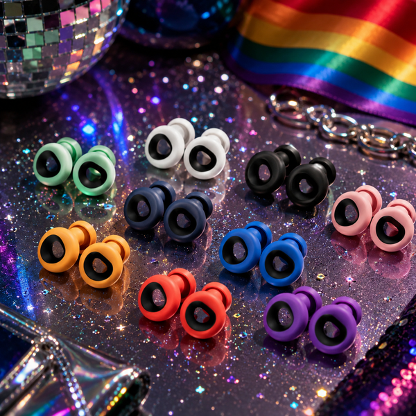 Flat lay of eight colorful pairs of ring-shaped earplugs on a glittery surface