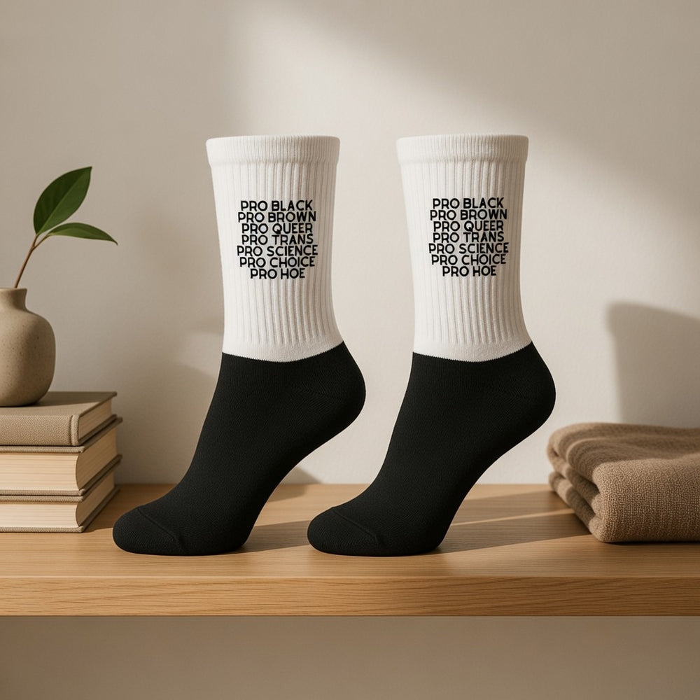 Pair of black-and-white crew socks reading “PRO BLACK,” “PRO BROWN,” “PRO QUEER,” “PRO TRANS,” “PRO SCIENCE,” “PRO CHOICE...