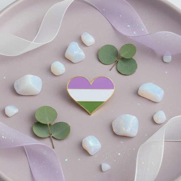 Genderqueer pride heart enamel pin with purple, white, and green stripes in a styled flat lay