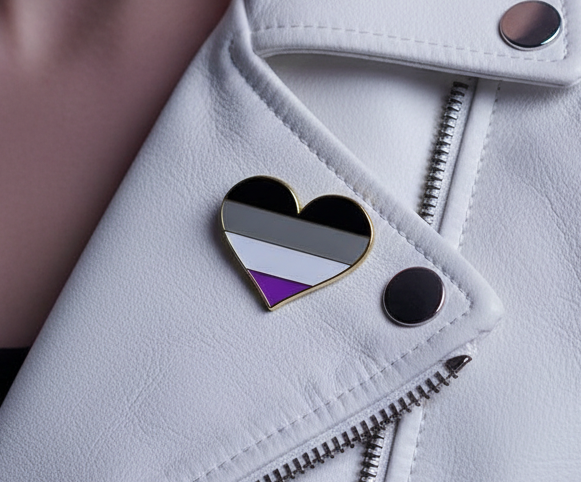 Asexual pride heart enamel pin on a white jacket with black, gray, white, and purple stripes
