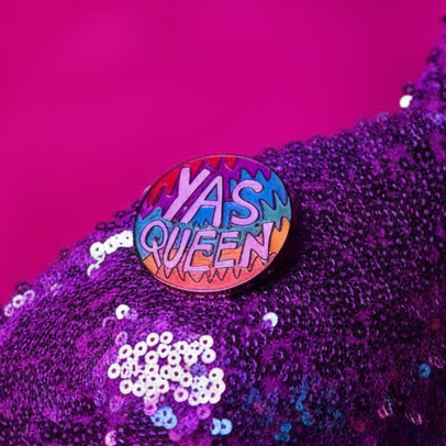 Yas Queen enamel pin with colorful lettering on purple sequined fabric