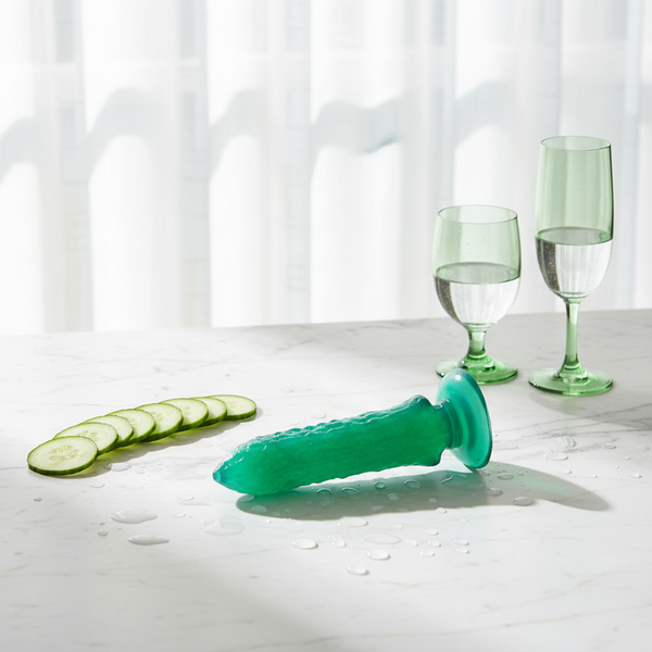 Turquoise textured dildo with a flared base beside cucumber slices and green wine glasses