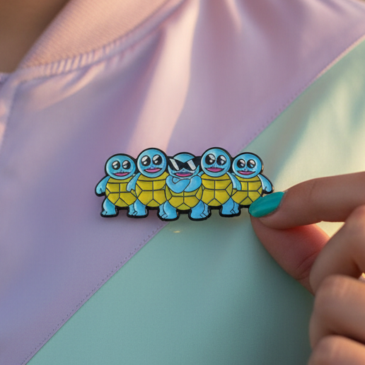 Close-up of the Cool Squirtle Crew Enamel Pin on a pastel garment. The pin features cartoon turtle figures with a central Squirtle Squad character, epitomizing queer pride and self-expression.