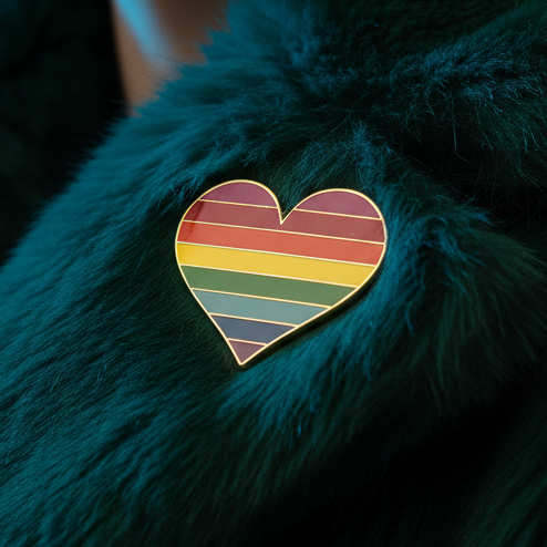 Trans pride heart enamel pin resting on dark teal faux fur