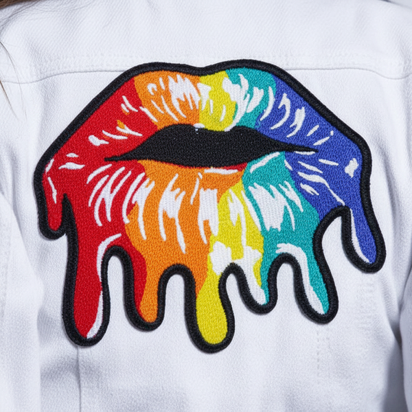 Close-up of a rainbow dripping lips embroidered iron-on patch on white fabric