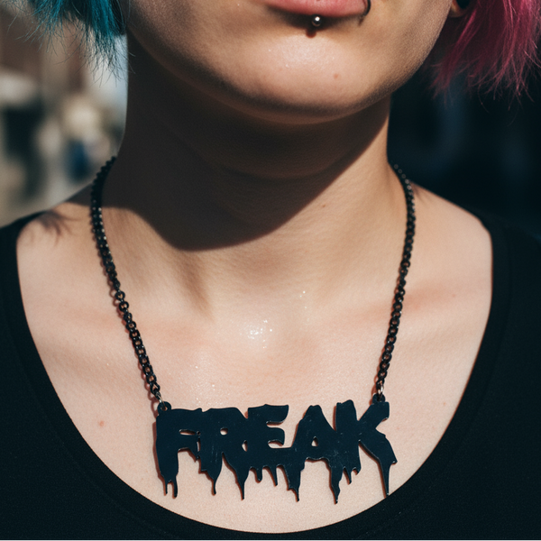 Close-up of a black acrylic “FREAK” statement necklace on a person