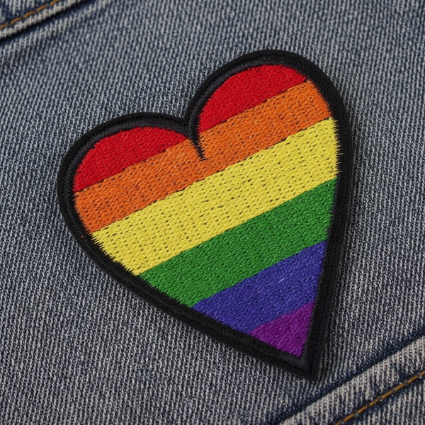 Close-up of a rainbow-striped heart embroidered iron-on patch on denim