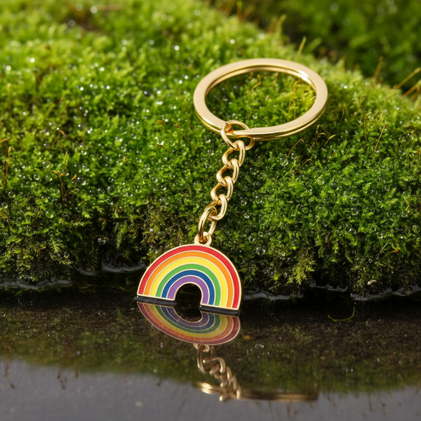Rainbow enamel keychain with gold-tone ring and chain on moss
