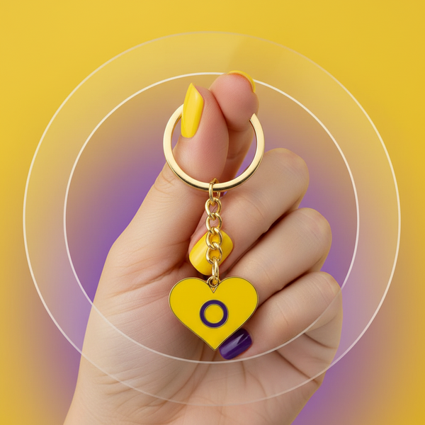 Intersex Pride heart keychain with yellow enamel charm and purple ring, held in a hand