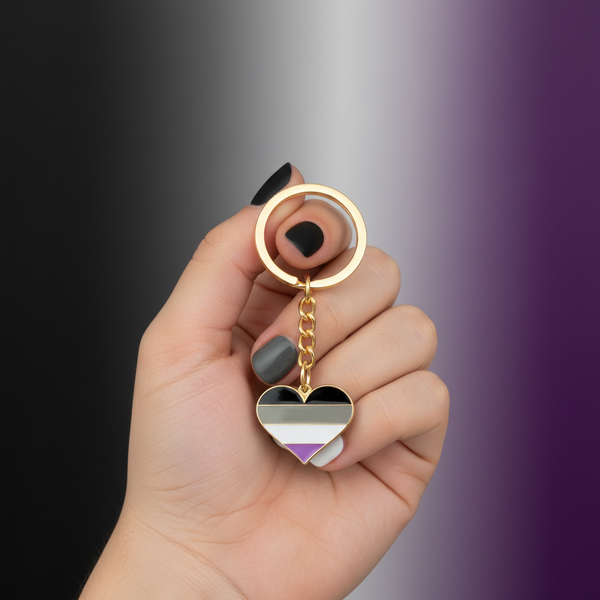 Hand holding an asexual pride heart keychain with black, gray, white, and purple stripes