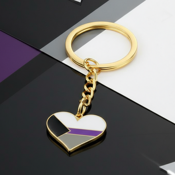 Gold heart keychain with the demisexual pride flag on a black-and-white surface