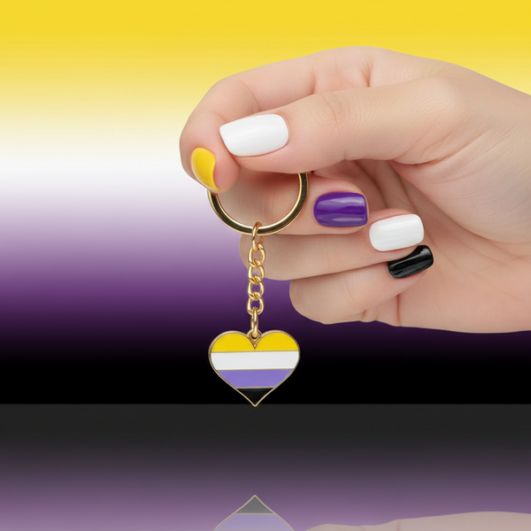 Hand holding a non-binary pride heart keychain with gold ring and chain