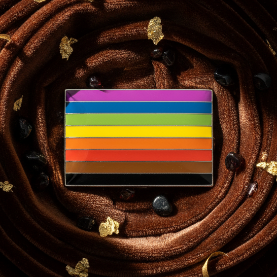 POC pride enamel pin with horizontal rainbow-colored stripes on brown fabric