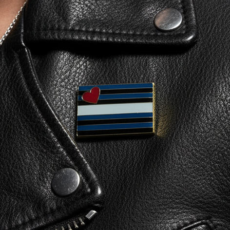 Close-up of a Leather Pride Enamel Pin on a black leather jacket, featuring black, dark-blue, and white stripes with a red heart, embodying empowerment and queer pride.