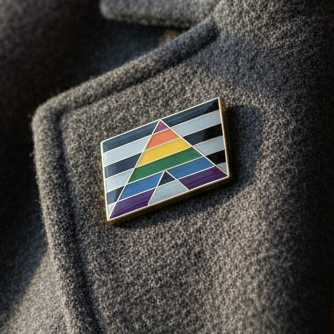 Straight Ally Enamel Pin on gray wool garment, featuring a stylized “A” with rainbow colors and black-and-white stripes, symbolizing LGBTQ+ allyship and pride, embodying visibility and self-expression.