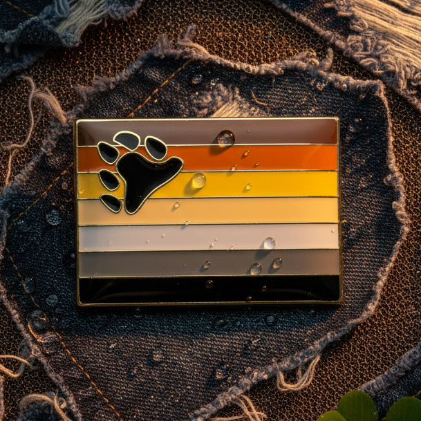 Bear pride enamel pin with black bear paw on brown, orange, yellow, cream, and black stripes