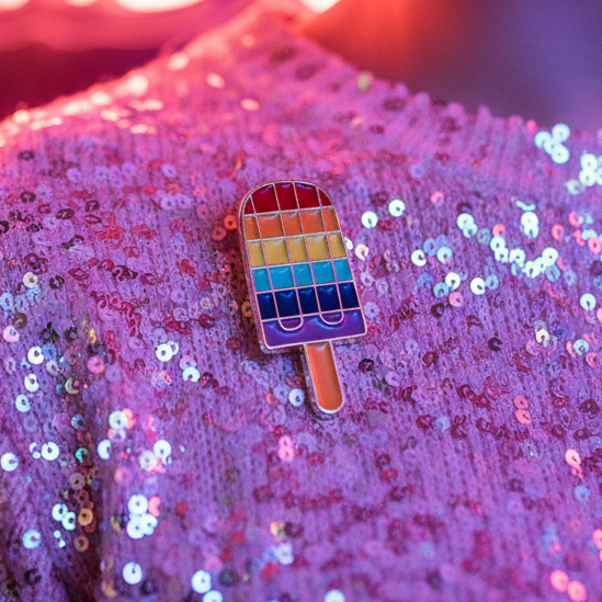 Rainbow popsicle enamel pin on shimmering purple sequined fabric