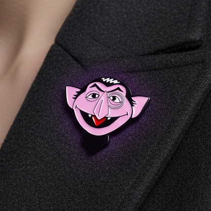 Pink Count Dracula enamel pin with black hair and red mouth on black fabric