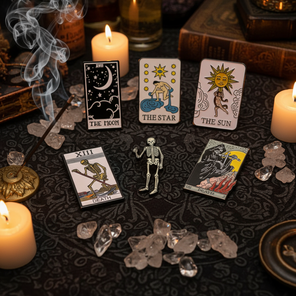 Tarot enamel pins displayed with Moon, Star, Sun, and Death cards among candles and crystals