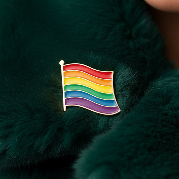 Rainbow LGBT Pride flag enamel pin resting on dark green faux fur
