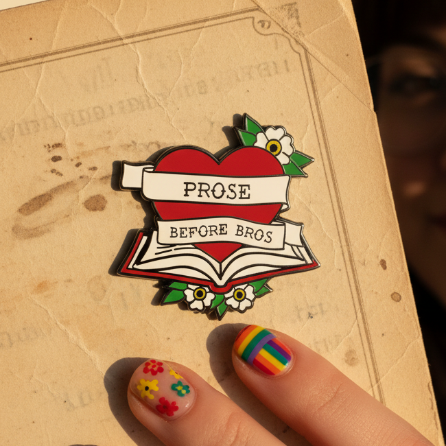Hand holding a “PROSE BEFORE BROS” enamel pin with a red heart, open book, and flowers