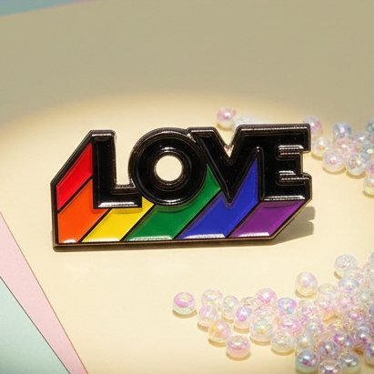 Love Is Love Rainbow Pride Enamel Pin featuring bold letters outlined in black, each filled with vibrant rainbow stripes. Photographed on a soft surface, surrounded by iridescent beads, exuding prideful and inclusive energy.
