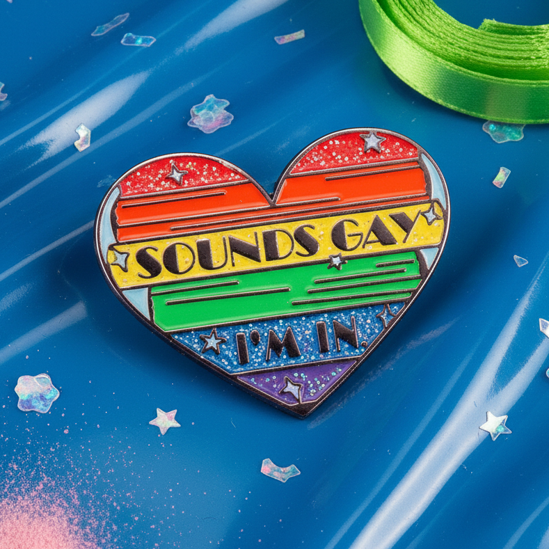 Heart-shaped enamel pin reading “SOUNDS GAY I'M IN” in rainbow stripes with stars
