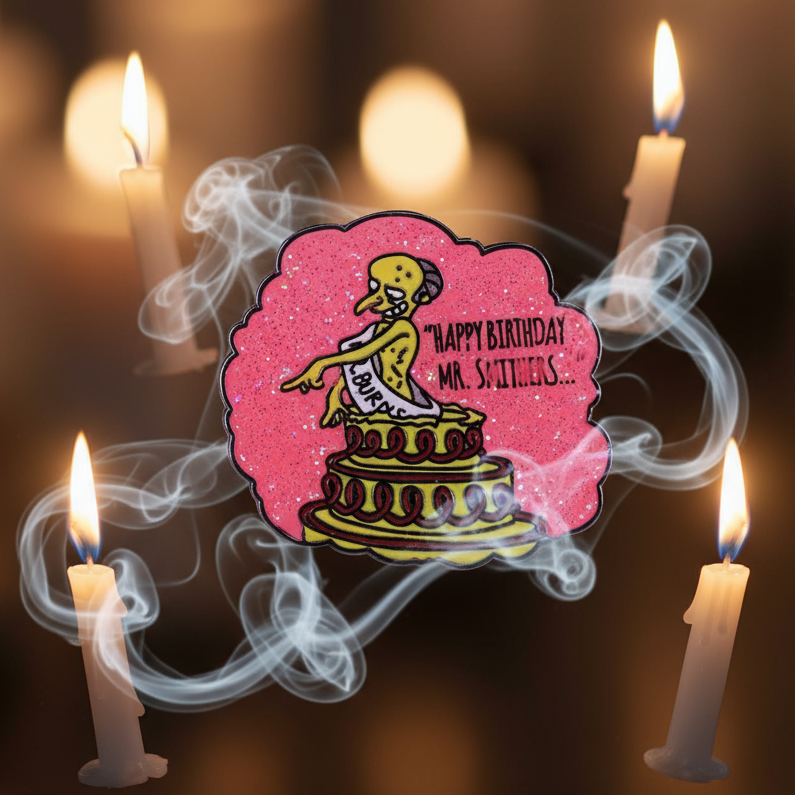 Enamel pin reading “Happy Birthday Mr. Smithers,” with a yellow cartoon figure on a pink glitter cake