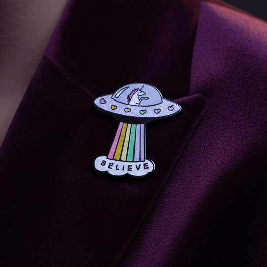 Unicorn spacecraft enamel pin with rainbow beam and “BELIEVE” banner