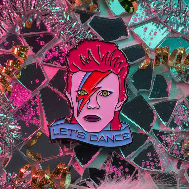 Let's Dance enamel pin featuring a pink, red-haired glam-rock face and blue banner