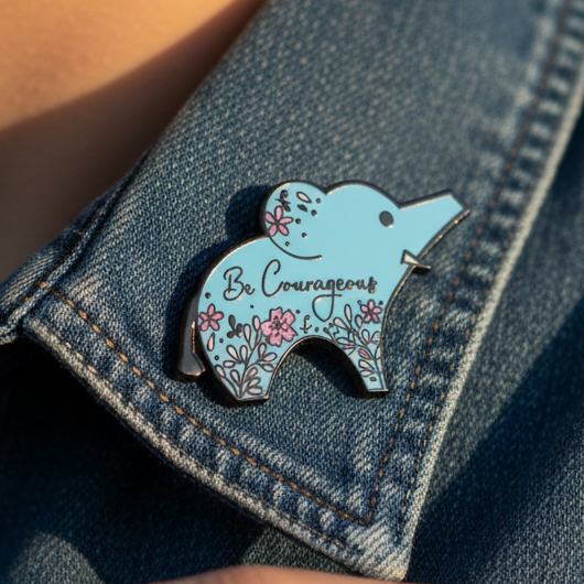 “Be Courageous” blue enamel bear pin with pink flowers on a denim jacket