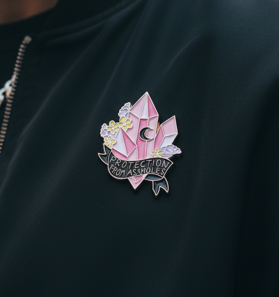 “Protection From Assholes” enamel pin with pink crystals, flowers, and crescent moon