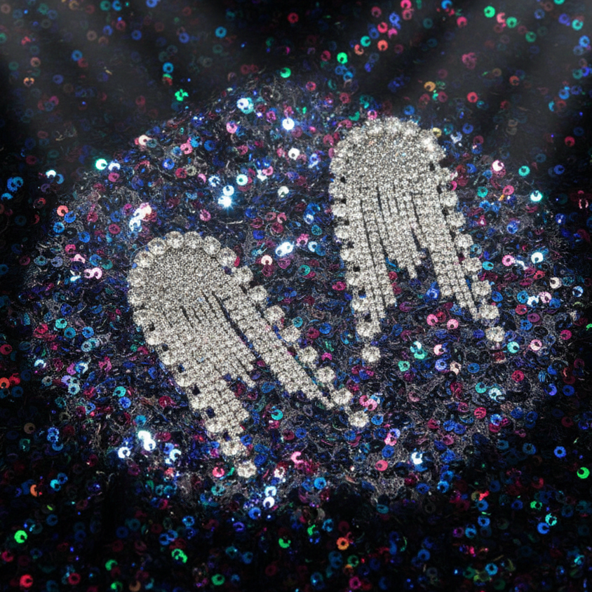 Silver rhinestone tassel earrings displayed on a multicolored sequin background