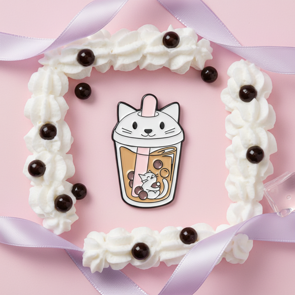 Milk tea enamel pin with a cat-shaped lid and cat illustration, styled on pink with whipped cream