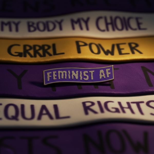 Purple and gold “FEMINIST AF” enamel pin on protest-message fabric