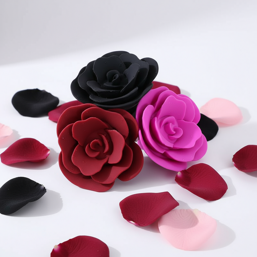 Three flower-shaped butt plugs in black, red, and magenta on a white surface with petals