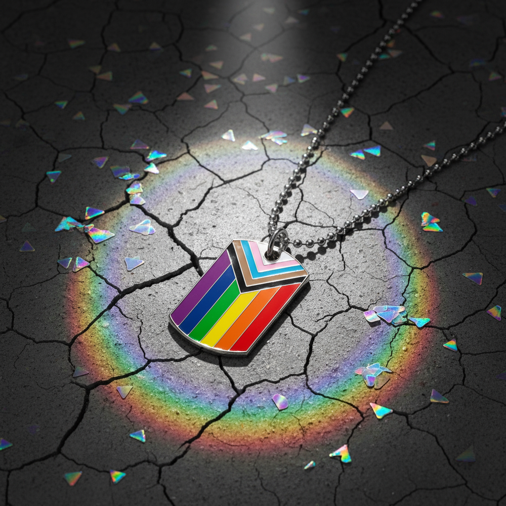 Progress Pride flag tag necklace on a ball chain, photographed on cracked dark ground