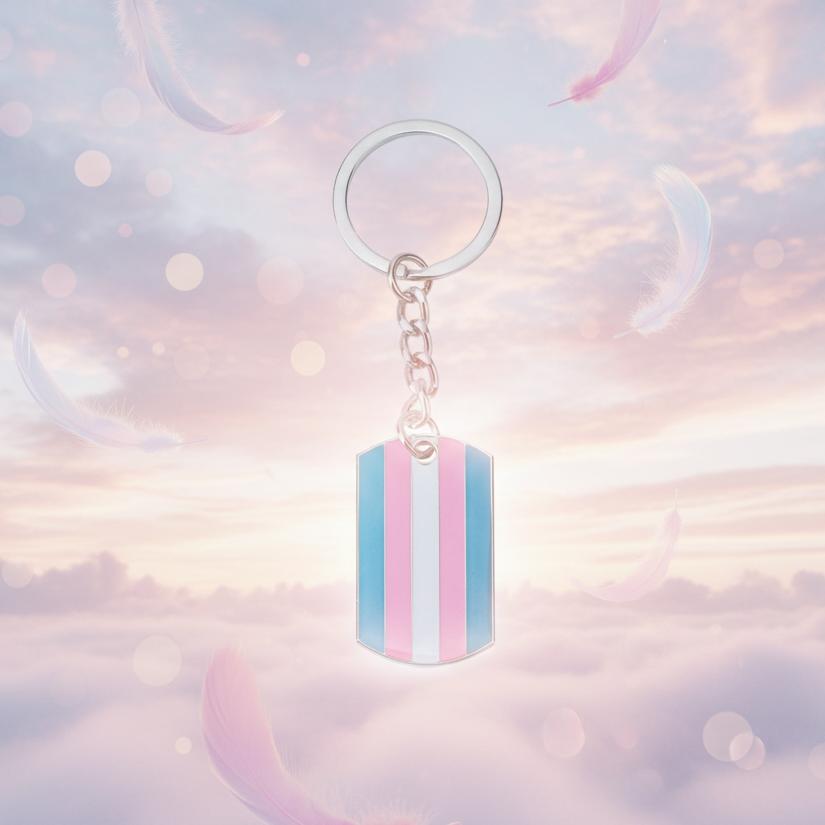 Transgender Pride keychain with a striped dog-tag pendant, photographed against a pastel sky