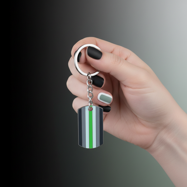 Agender pride keychain with black, gray, white, and green striped tag held by a hand